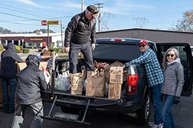 Volunteers unloading food bags from pickup
